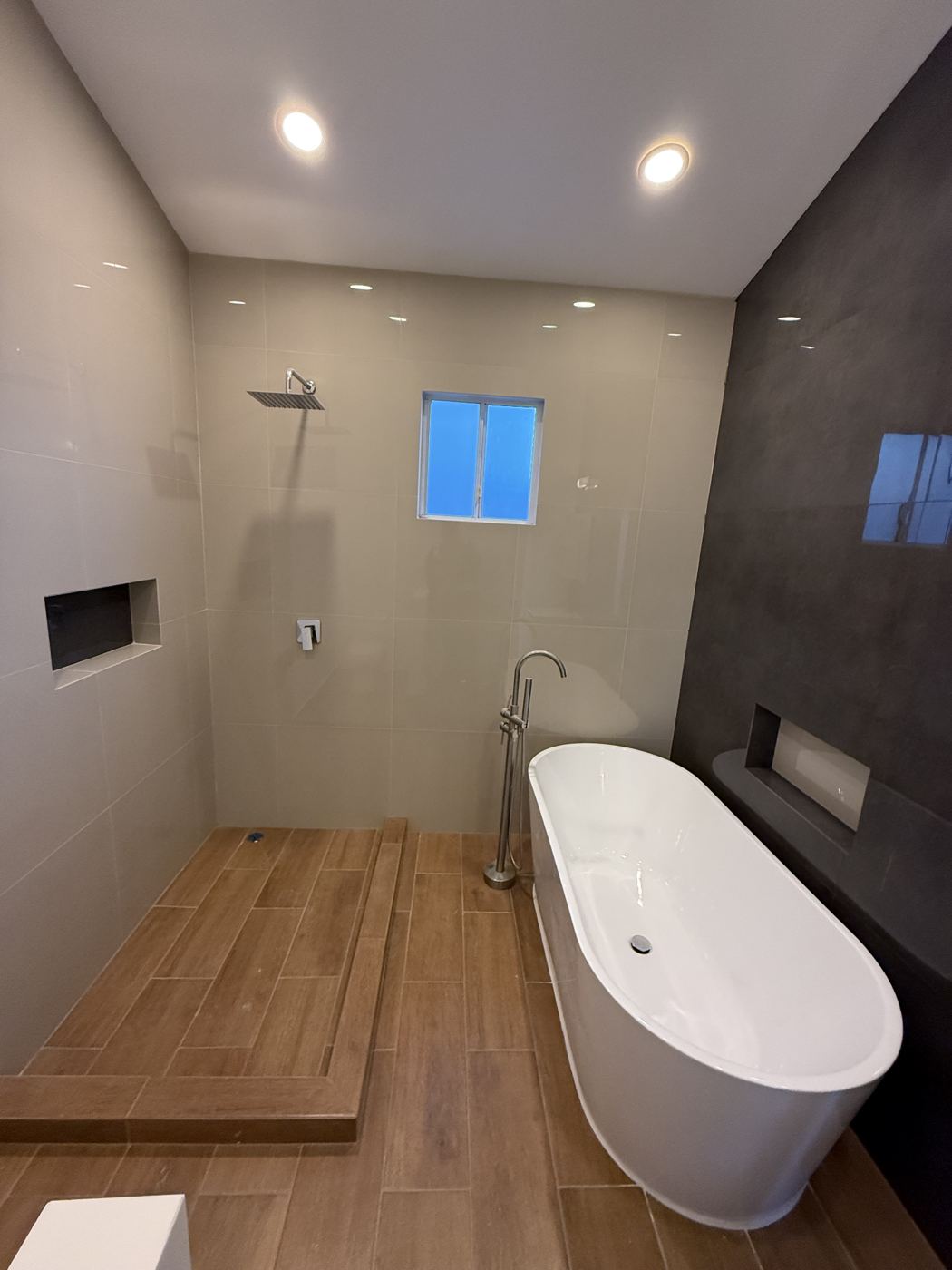 Baño remodelado con tina independiente y piso tipo madera