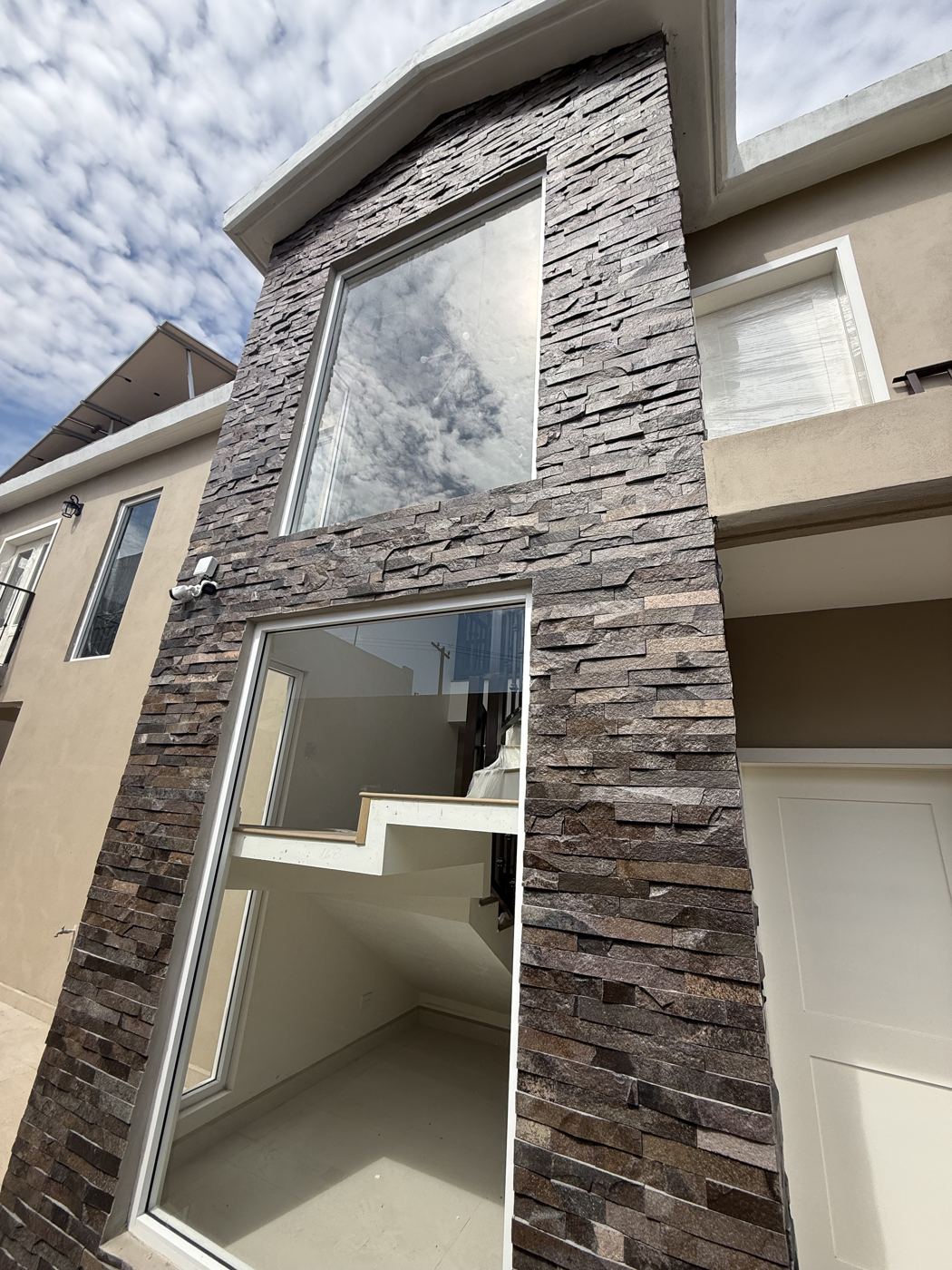 Ampliación de casa con fachada de piedra y ventanales